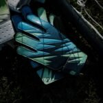 youth goalie gloves resting on grass near a net.