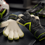 youth goalie gloves in carbon black and volt yellow with 4mm latex palm displayed beside a soccer ball and cleats in a professional studio gear review setup